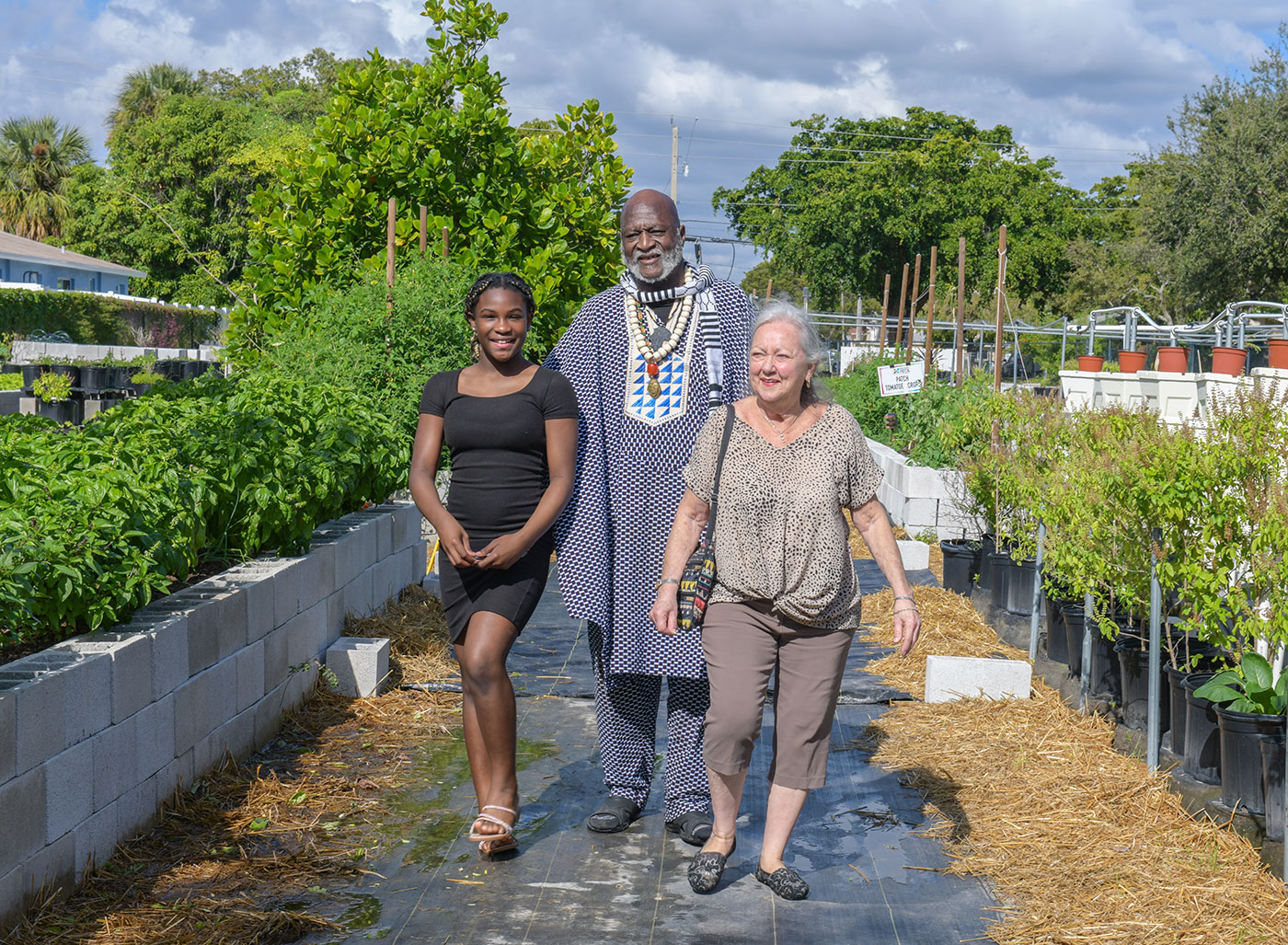 A student walking through the Earth 2 Table garden with two mentors