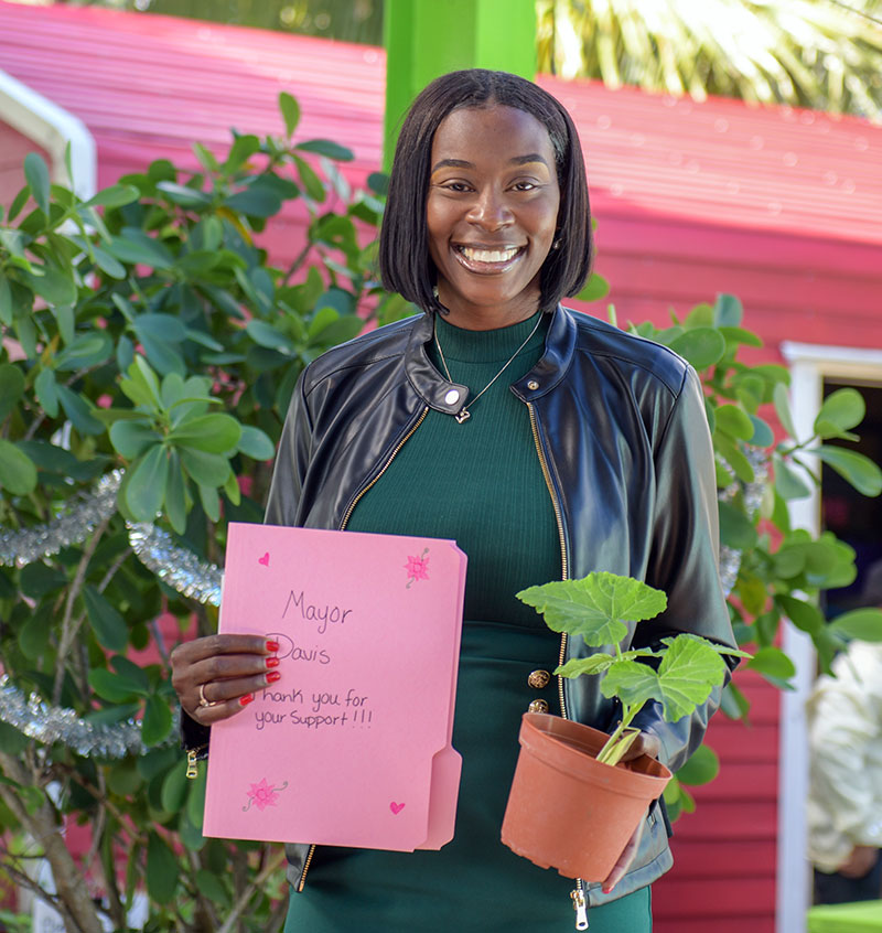 Mayor Davis holding a student thank-you card and a potted seedling