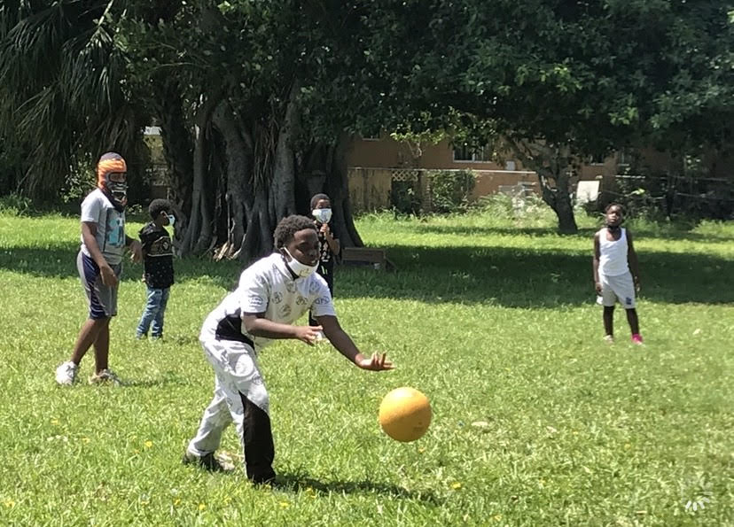 Student tossing a ball during outdoor play at the park