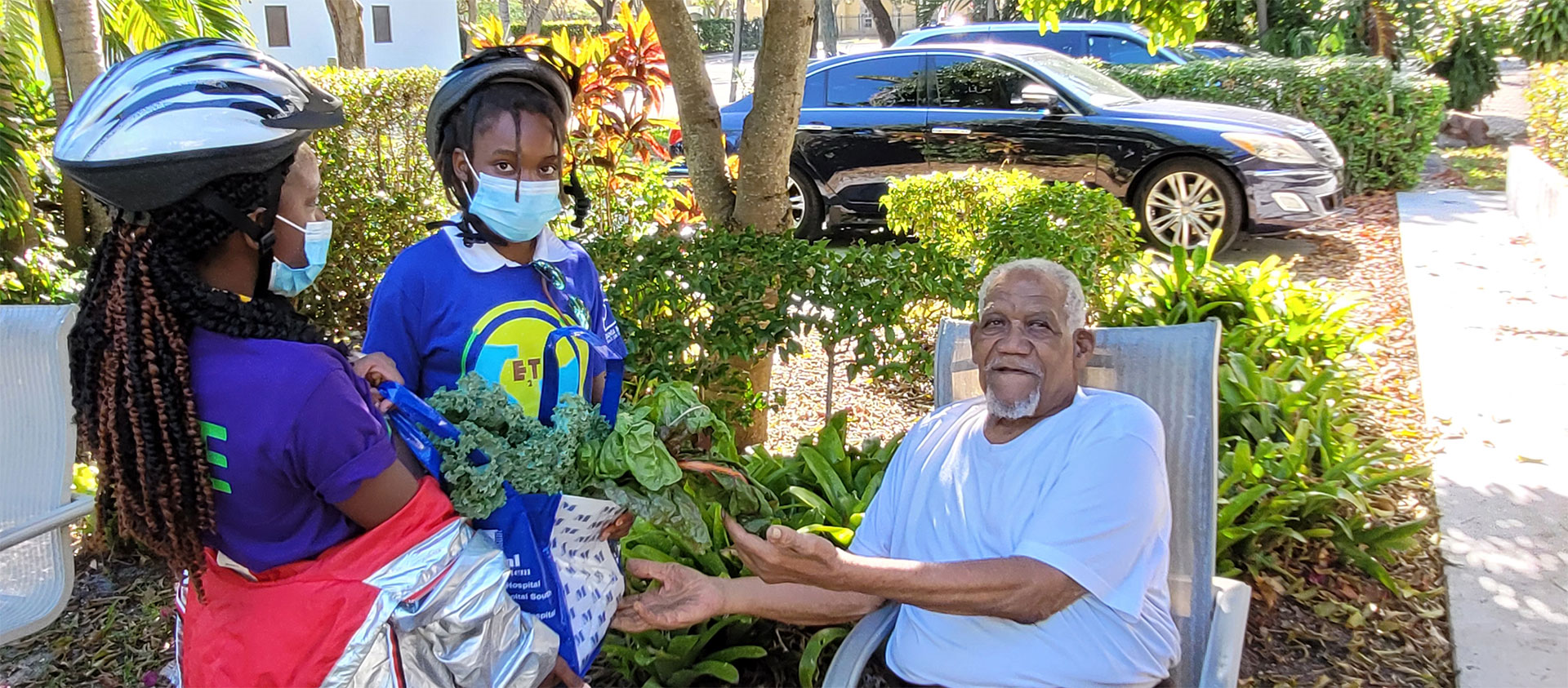 Students delivering fresh garden greens to a neighbor