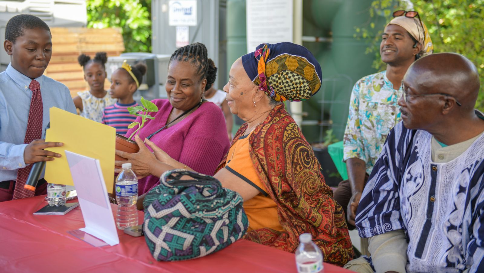 A student presenting a seedling to community elders at an Earth 2 Table event