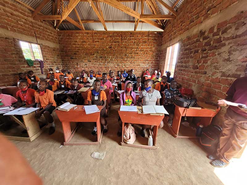 Students seated at desks in a brick classroom during a mission visit