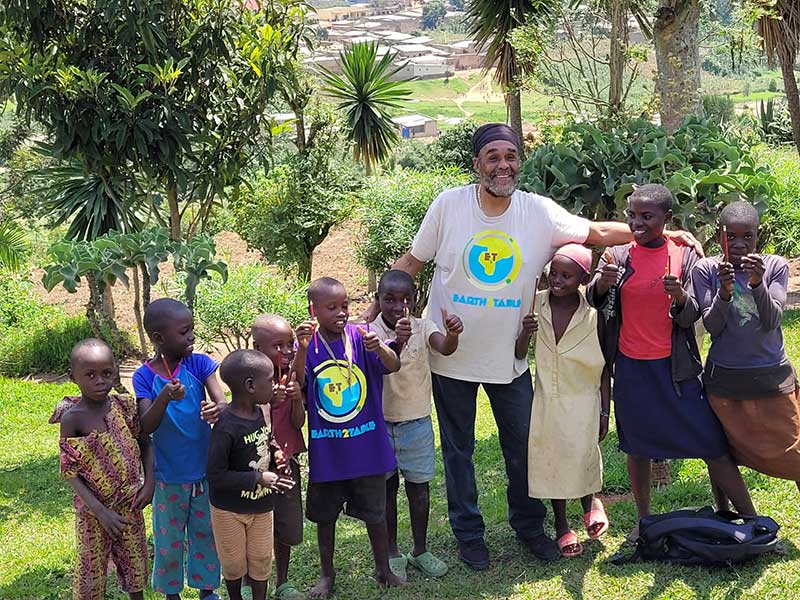 Mentor in an Earth 2 Table shirt with children on a hillside garden