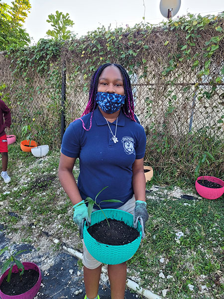 Student holding a teal pot with a young seedling