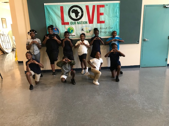 Students posing with heart hands under the Love Our Nation banner